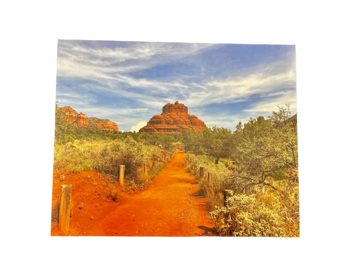 Scenic view of a desert landscape with red rock formations and a dirt path.
